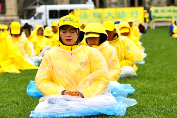 Falun Gong adherents demonstrate a meditation exercise on Parliament Hill during Falun Dafa Day celebrations on May 8, 2024. (Jonathan Ren/The Epoch Times)