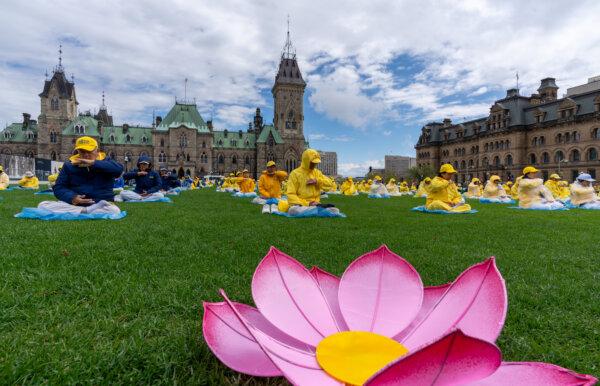 Falun Gong adherents demonstrate a meditative exercise during Falun Dafa Day celebrations on Parliament Hill in Ottawa on May 8, 2024. (James Zhou/The Epoch Times)