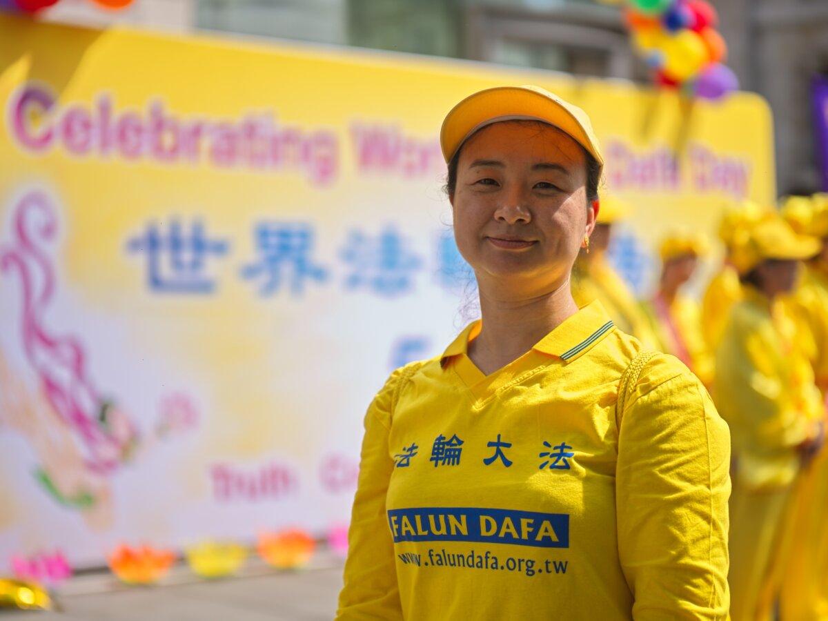 A Falun Gong practitioner stands in front of a banner at an annual event in celebration of the World Falun Dafa Day, in London on May 11, 2024. (Yanning Qi/The Epoch Times)