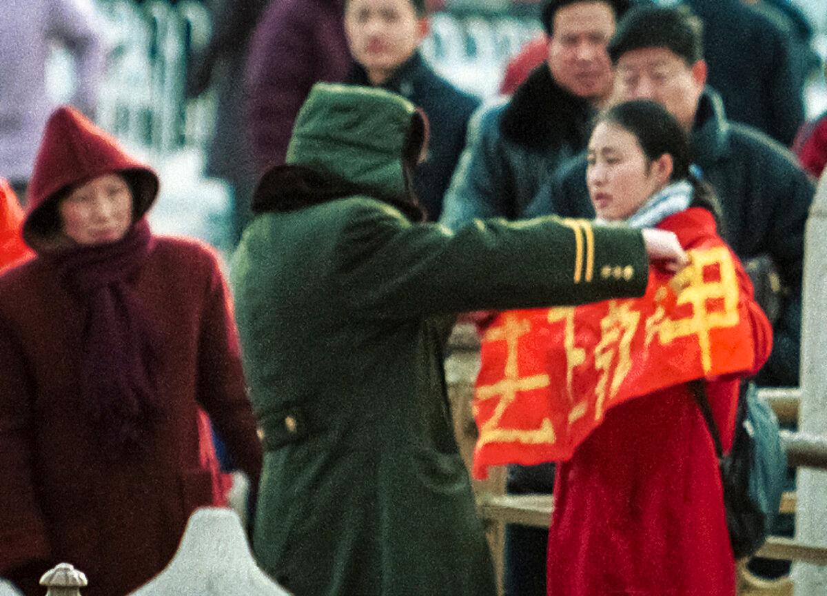 A woman who holds up a Falun Gong banner is detained by police at Beijing's Tiananmen Gate in China, on Jan. 25, 2001. (AP Photo/Greg Baker)