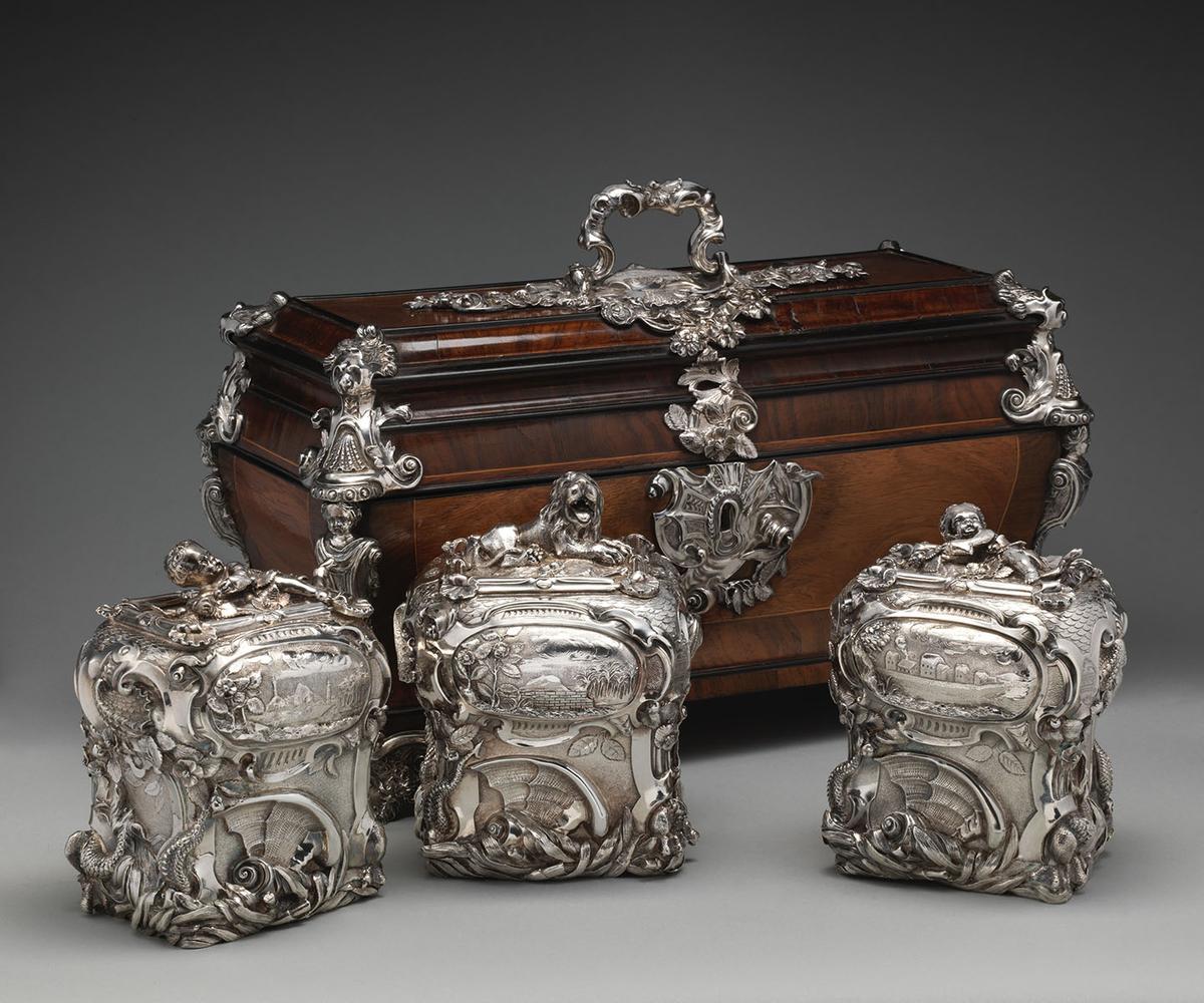 A pair of tea caddies and a sugar box in a case, 1738 and/or 1739, by Paul de Lamerie. Silver; oak, rosewood with boxwood and ebony inlay, silver mounts. The Metropolitan Museum of Art, New York City. (Public Domain)