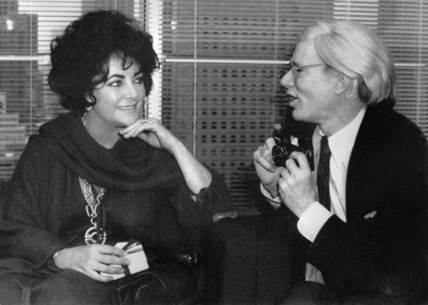 Andy Warhol (R) asks actress Elizabeth Taylor for permission to take a picture of her at the opening of designer Halston's new salon in New York City on Feb. 13, 1978. (AFP/Getty Images)