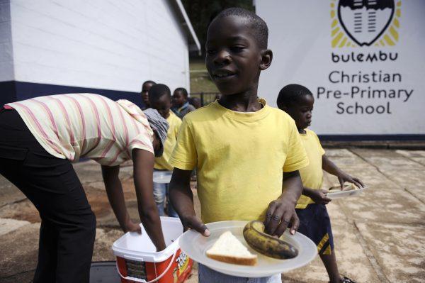 A boy holds a plate as pupils queue for lunch in a school for children orphaned by AIDS on March 1, 2012 in the town of Bulembu in Swaziland. Swaziland has the world's highest rate of HIV infection, with at least one in four adults carrying the virus, and about 120,000 children have been orphaned, comprising more than 10 percent of the total population. (Stephane de Sakutin/AFP/Getty Images)