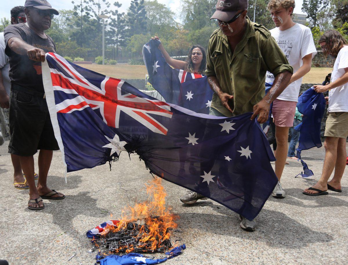 Aboriginal protesters burn an Australian flag during a rally in coincidence with the G-20 summit in Brisbane, Australia, Sunday, Nov. 16, 2014. (AP Photo/Dean Saffron)