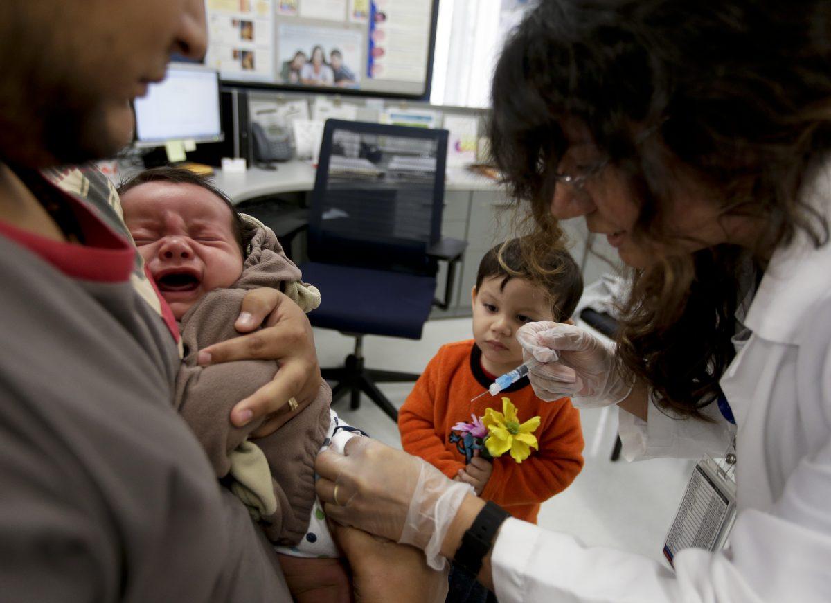 A registered nurse at the San Diego Public Health Center gives an infant a whooping cough injection as his brother watches on Dec. 10, 2014. (Chris Carlson/AP Photo)