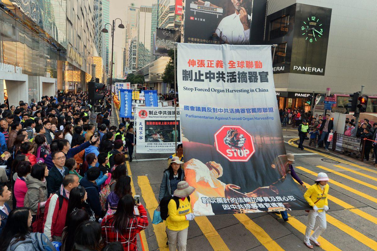 Falun Gong practitioners hold a banner that reads "Stop Forced Live Organ Harvesting" during a march through the business district of Tsim Sha Tsui on Hong Kong's Kowloon Peninsula on Jan. 17, 2015. (Song Pi-lung/The Epoch Times)