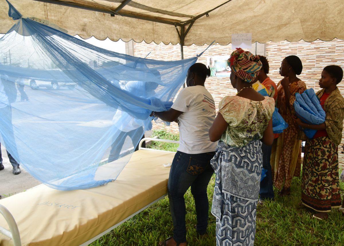 People demonstrate how to put a mosquito net on a bed during a free distribution of insecticide-treated mosquito nets at the town hall in the Port-Bouet district of Abidjan, Ivory Coast, on April 24, 2015. (Sia Kambou/AFP/Getty Images)