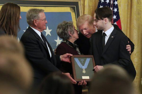 President Donald Trump awards the Medal of Honor to Army Staff Sgt. Travis Atkins and leans forward to join Atkin's son Trevor Oliver, right, and his parents John and Elaine Atkins of Bozeman, Mont., after accepting the posthumous recognition for conspicuous gallantry in Iraq in June 2007, in the East Room of the White House, in Washington, on March 27, 2019. (Manuel Balce Ceneta/AP Photo)