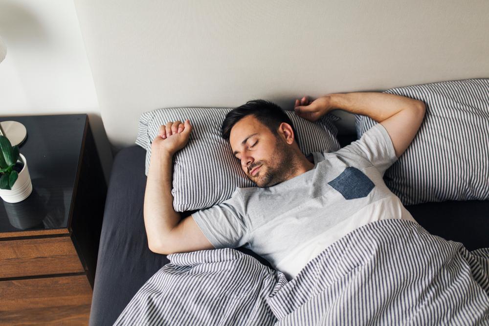 Illustration - Shutterstock | <a href="https://www.shutterstock.com/image-photo/young-man-sleeping-alone-on-his-1144829765">Jelena Zelen</a>