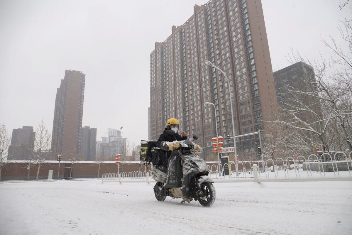 A food delivery worker rides his bike amid snow at a residential compound in Beijing, China, on Feb. 6, 2020. (Reuters)