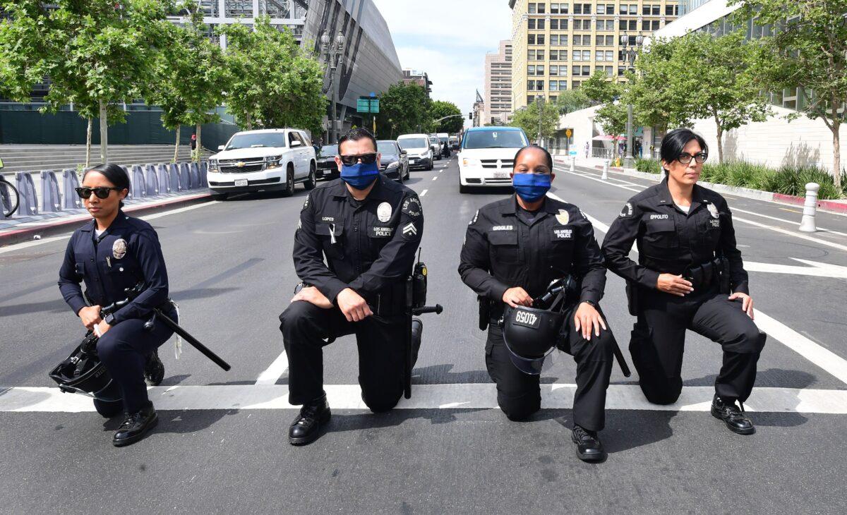 Los Angeles Police Department officers kneel during a rally led by Baptist Ministers to City Hall in memory of George Floyd, on June 2, 2020. The city has paid $20 million so far in settling lawsuits resulting from the 2020 riots. (Frederic J. Brown/AFP via Getty Images)