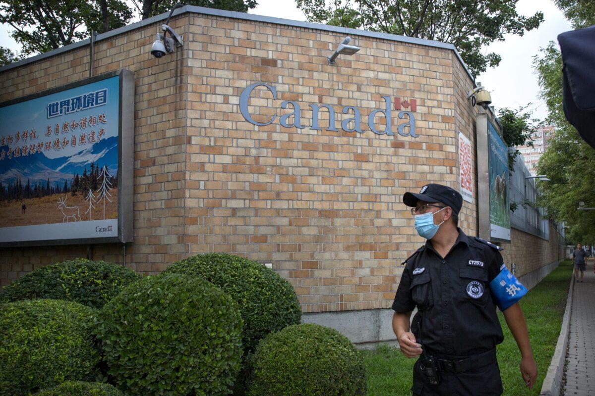 A security officer stands outside the Canadian Embassy in Beijing on Aug. 6, 2020. (AP Photo/Mark Schiefelbein)