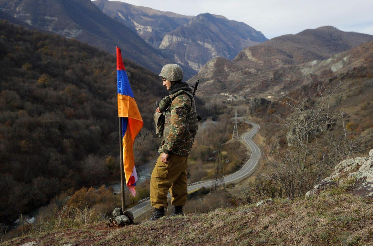 An Armenian soldier stands guard next to Nagorno-Karabakh's flag atop the hill near Charektar in the separatist region of Nagorno-Karabakh on Nov. 25, 2020. (Sergei Grits/AP Photo)