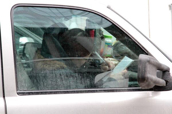 A woman writes while sitting in her vehicle that is part of the protest blockade in Ottawa. (Richard Moore/The Epoch Times)
