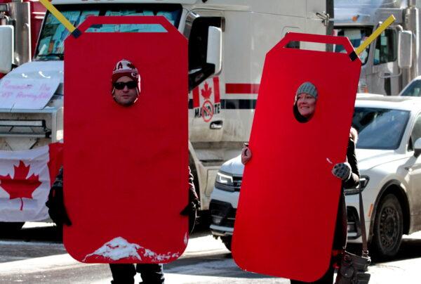 After police tried to stop supplies of gas to the truckers Stephen Gilbert (L) and Ashleigh Laughren, of Perry Sound, Ontario, decided to have unique protest placards. (Richard Moore/The Epoch Times)