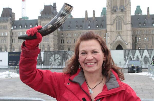 Benita Pedersen raises a steer's horn that symbolizes strength in Ottawa. During the protest, she led religious "Jericho Walks" around the parliamentary precinct. (Richard Moore/The Epoch Times)