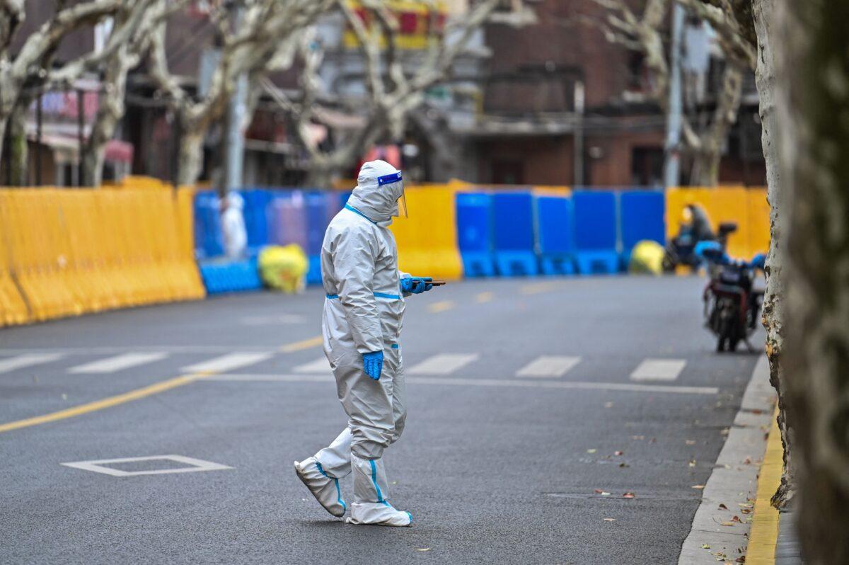 A worker, wearing protective gear, walking next to barriers during a lockdown in Jing'an district, in Shanghai on March 31, 2022. (Hector Retamal/AFP via Getty Images)