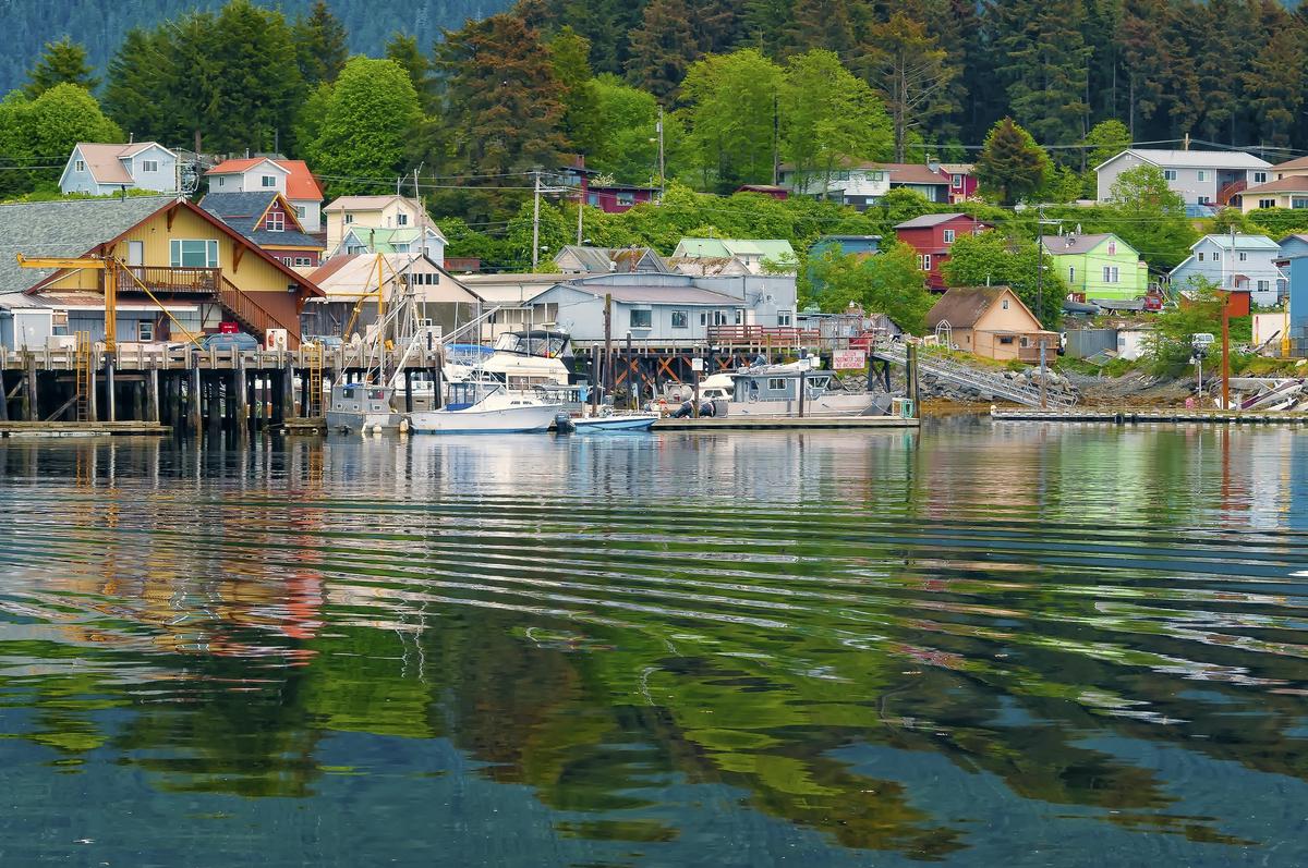 Houses, buildings, and boats reflected on the water of Sitka, Alaska, an island community on the inside passage of coastal Alaska near the Pacific Ocean, and a cruise ship destination. (Dreamstime)