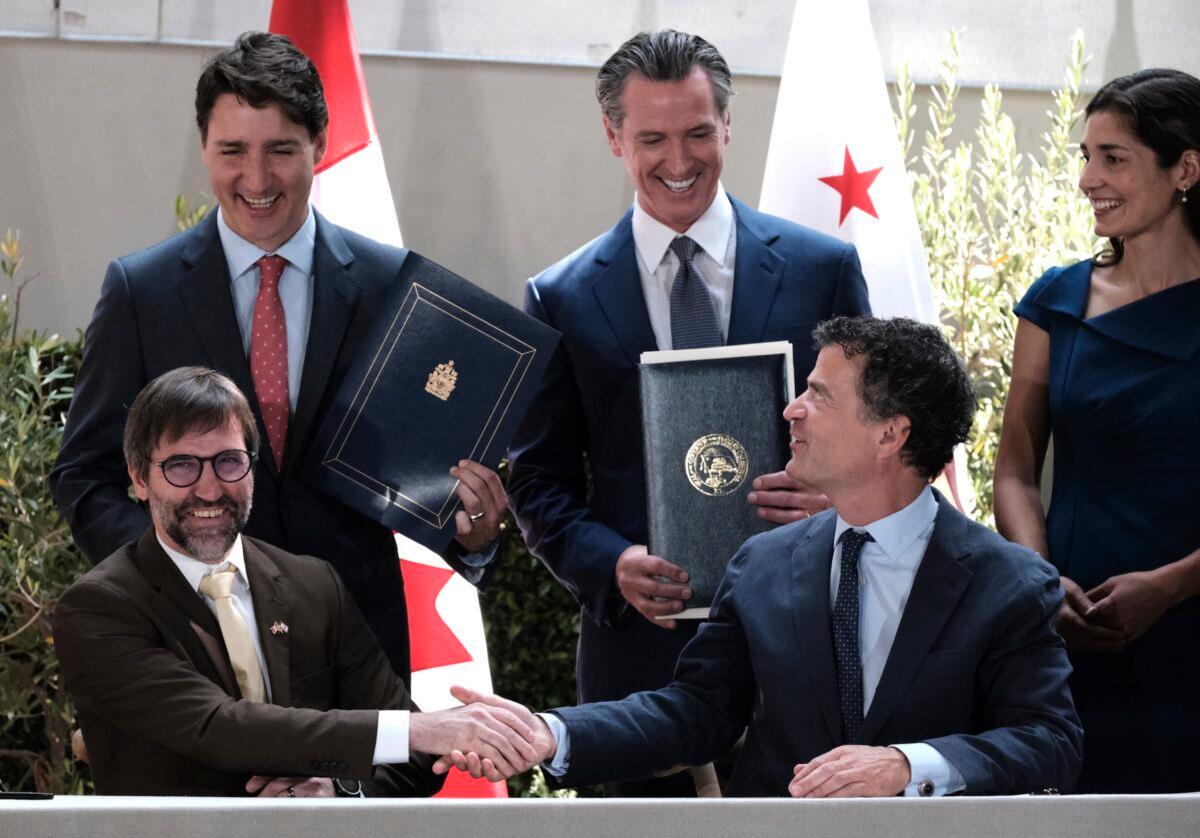 Then-Prime Minister Justin Trudeau (back L) celebrates with California Gov. Gavin Newsom (C) and California Senior Climate Adviser Lauren Sanchez (back R), as Then-Environment Minister Steven Guilbeault (front L) and California Senior Environmental Protection Agency Chief Jerod Blumenthal sign a memorandum of cooperation on climate change at the California Science Center outside the ninth Summit of the Americas, in Los Angeles on June 9, 2022. (Richard Vogel/AP Photo)