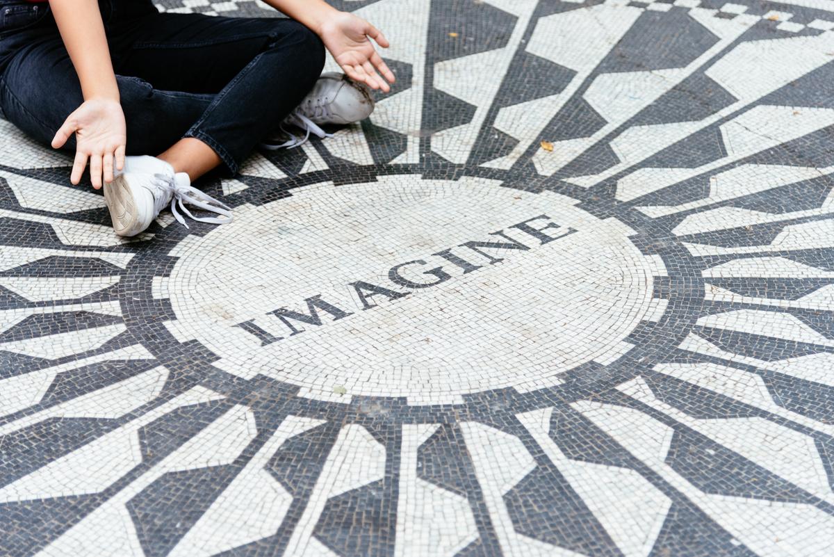 Young woman sitting on the Imagine mosaic in the Strawberry Fields in Central Park. (Dreamstime)