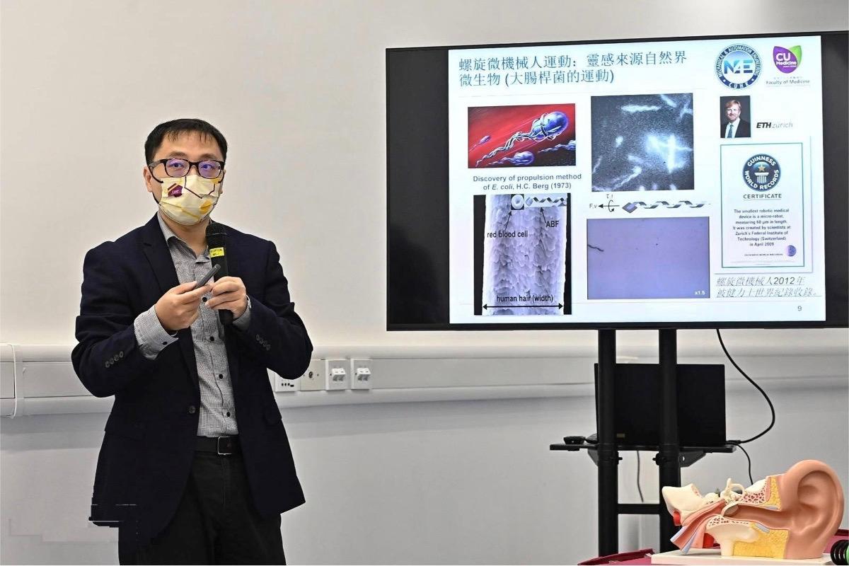 Zhang Li, Professor of the Department of Mechanical and Automation Engineering at CUHK, points out in this demonstration that the technology originates from the movement simulation of Escherichia coli flagella, which is controlled by a magnetron to scrape the bacterial membrane in the middle ear duct. (Sung Pi-lung/The Epoch Times)