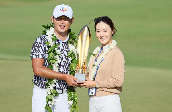 Si Woo Kim of South Korea poses with his wife Ji Hyun Oh and the trophy after putting in to win on the 18th green during the final round of the Sony Open in Hawaii at Waialae Country Club in Honolulu on Jan. 15, 2023. (Andy Lyons/Getty Images)