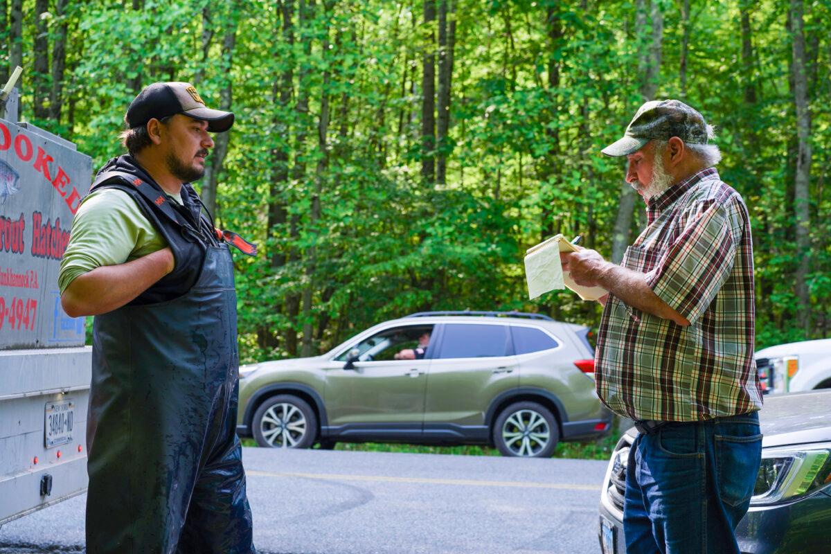 Orange County Federation of Sportsmen's Clubs Chairman Jack Michulski (R) keeps count of trout stocked in Otisville, N.Y., on May 23, 2023. (Cara Ding/The Epoch Times)