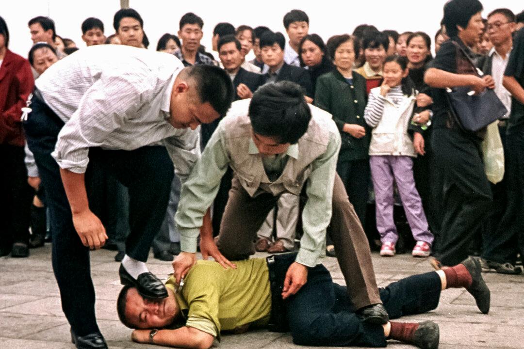 Police detain a Falun Gong protester in Tiananmen Square as a crowd watches in Beijing Sunday Oct. 1, 2000. Followers of the outlawed Falun Gong sect chanted slogans and raised yellow banners on Tiananmen Square Sunday in a burst of protest that defied heavy security meant to ensure patriotic celebrations of China's National Day. (AP Photo/Chien-min Chung)