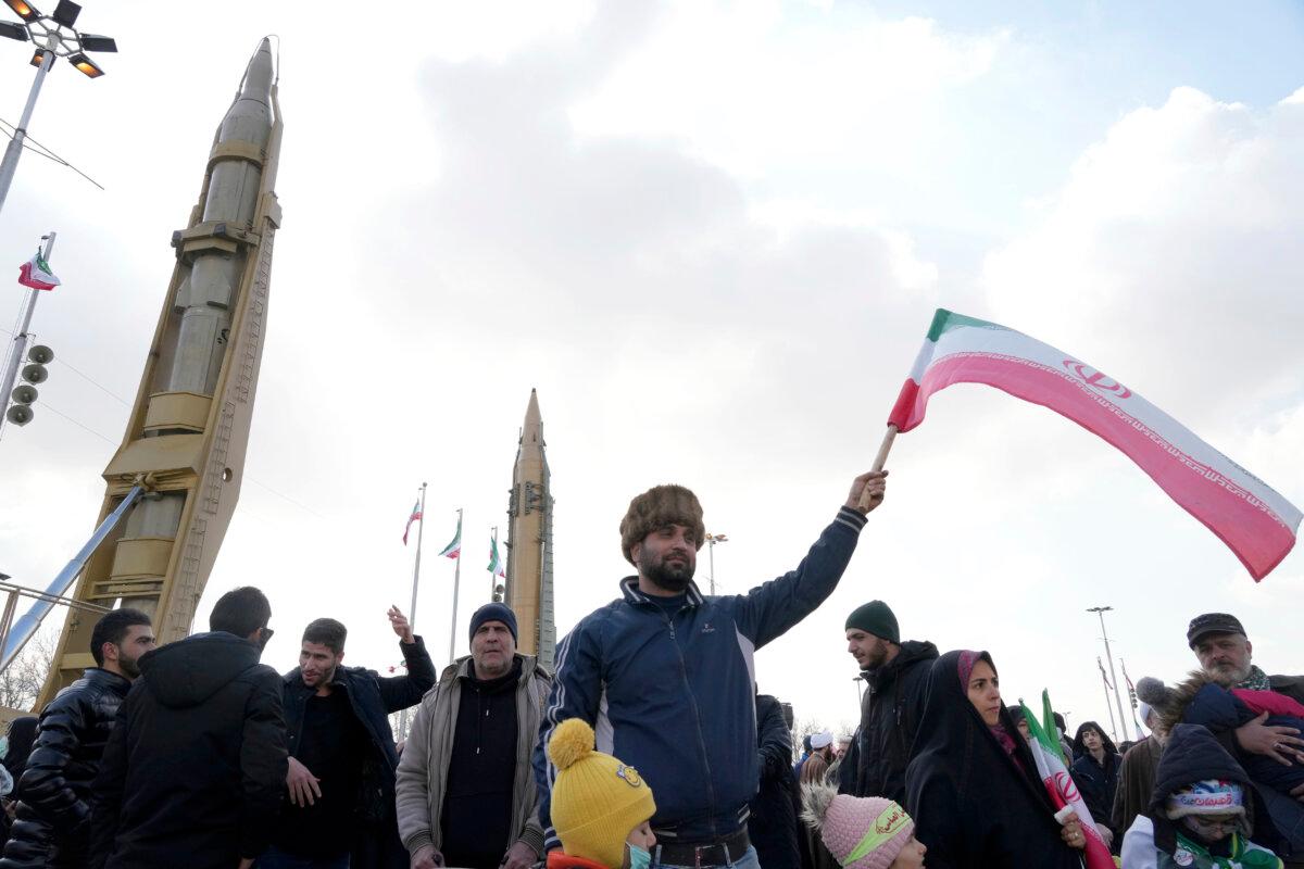 A man waves a flag as domestically built missiles are displayed in the background during the annual rally commemorating Iran's 1979 Islamic Revolution, in Tehran, Iran, on Feb. 11, 2023. (Vahid Salemi/AP)