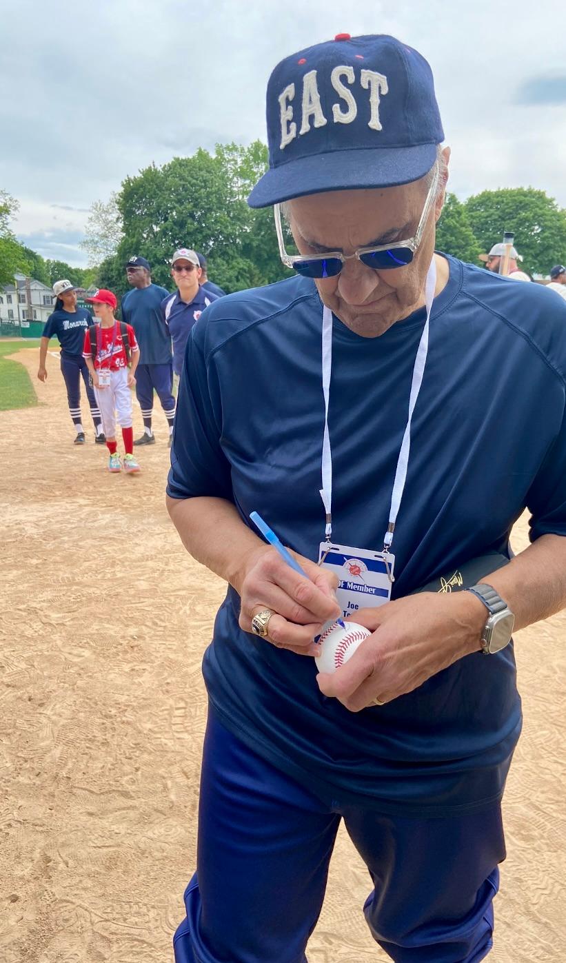 Joe Torre, wearing an EAST cap, the team he coached, signed on a baseball during the East-West All-Star Game at Doubleday Field in Cooperstown, New York on May 25, 2024. (Donald Laible/The Epoch Times)