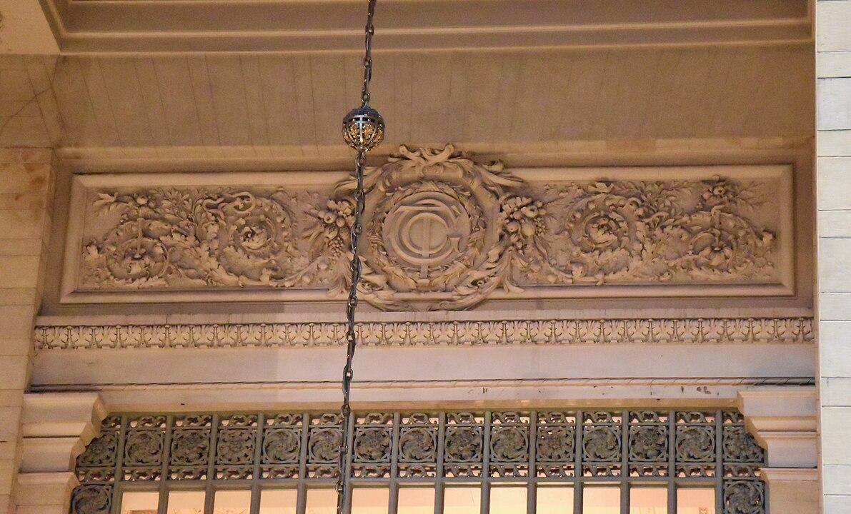 The Vanderbilt family, prominent in New York City at the time of the station’s construction, had their signature motifs, acorns, and oak leaves, connoting strength and longevity, displayed on a frieze over a window in the Main Concourse. A sculpted wreath has overlapping letters “G,” “C”, and “T,” (Grand Central Terminal). Intertwined in the initials are elements of an anchor and a railroad spike representing Vanderbilt’s involvement in the shipping and ferry industry. <span style="font-size: 16px;">(</span><a style="font-size: 16px;" href="https://commons.wikimedia.org/wiki/User:%E2%B1%AE">Ɱ</a><span style="font-size: 16px;">/</span><a style="font-size: 16px;" href="https://creativecommons.org/licenses/by-sa/4.0">CC BY-SA 4.0</a><span style="font-size: 16px;">)</span>
