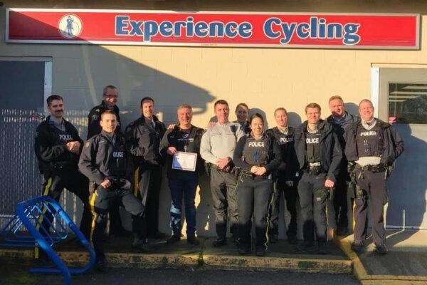 Will Arnold is awarded a challenge coin by police officers outside his shop, Experience Cycling, in Duncan, B.C. (Courtesy of Will Arnold)