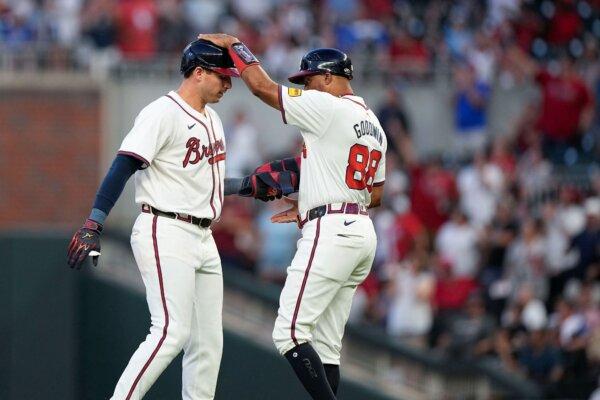 Austin Riley (L) of the Braves receives congratulations from first-base coach Tom Goodwin after smacking a double against the Giants in Atlanta on July 3, 2024. (Brynn Anderson/AP Photo)