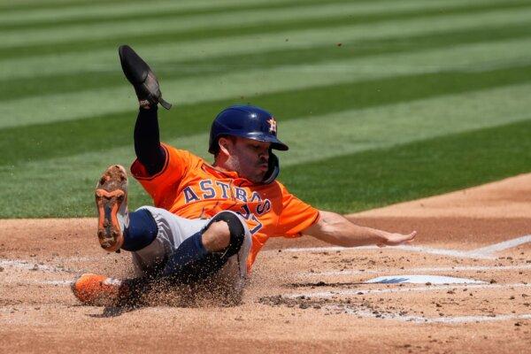 Jose Altuve of the Astros swipes the plate with his hand while sliding in to score a run against the A's in Oakland, Calif., on July 24, 2024. (Godofredo A. Vásquez/AP Photo)