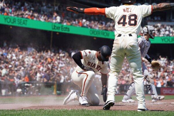 The Giants' Derek Hill, who also scored on the play, signals that teammate Jorge Soler is safe at the plate against the Rockies in San Francisco on July 28, 2024. (Kavin Mistry/AP Photo)