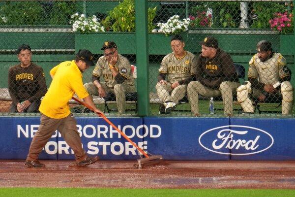 A member of the grounds crew squeegees water off the PNC Park warning track in front of the San Diego Padres' bullpen during a rain delay in Pittsburgh on Aug. 6, 2024. (Gene J. Puskar/AP Photo)