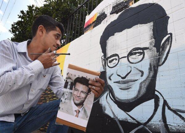 Artist Levi Ponce poses with his mural project of murdered journalist Daniel Pearl, near his old neighborhood in Los Angeles on May 23, 2015. The artist worked with students from the Daniel Pearl High School and LAPD West Valley Police cadets on the project. (Mark Ralston/AFP via Getty Images)