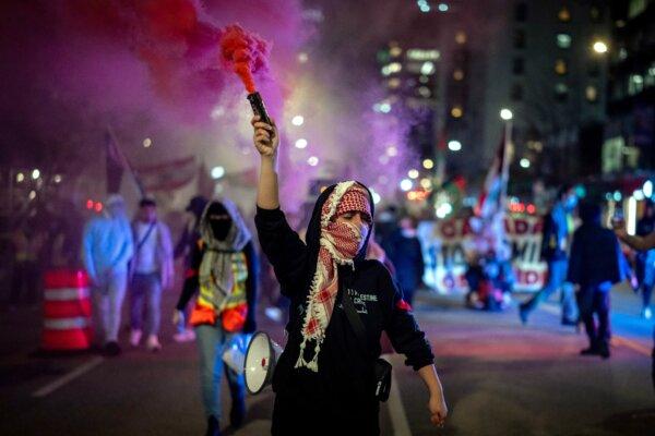 A demonstrator holds a smoke bomb while marching during a pro-Palestinian rally marking the anniversary of the Hamas attack on Israel last October, in Vancouver on Oct. 7, 2024. (The Canadian Press/Ethan Cairns)