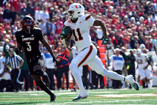 Miami wide receiver Samuel Brown (11) during the first half of an NCAA college football runs from the pursuit of Louisville defensive back Quincy Riley (3) to score game in Louisville, Ky., Saturday, Oct. 19, 2024. (Timothy D. Easley/AP Photo)