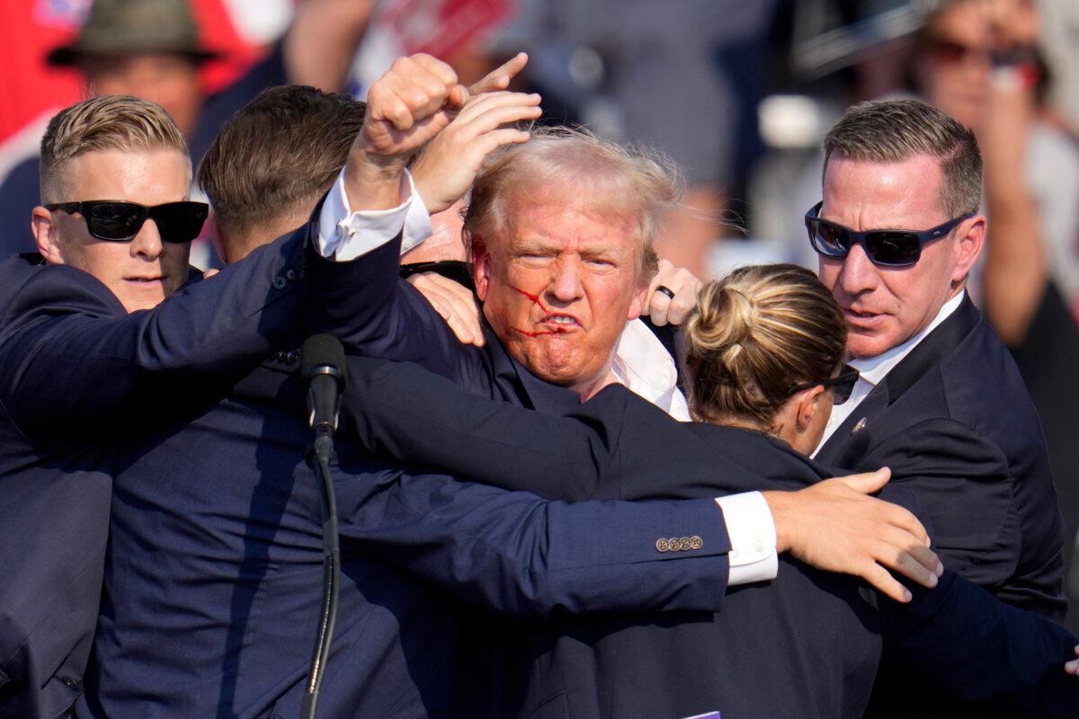 Republican presidential candidate former President Donald Trump pumps his fist as he is helped off the stage at a campaign event in Butler, Pa., on July 13, 2024. (Gene J. Puskar/AP Photo)