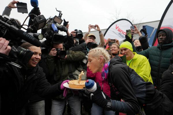 Belgian ultra runner Hilde Dosogne, (C), blows out candles on a cake after crossing the finish line of her 366th consecutive marathon in Ghent, Belgium, on Dec. 31, 2024. (Virginia Mayo/AP Photo)