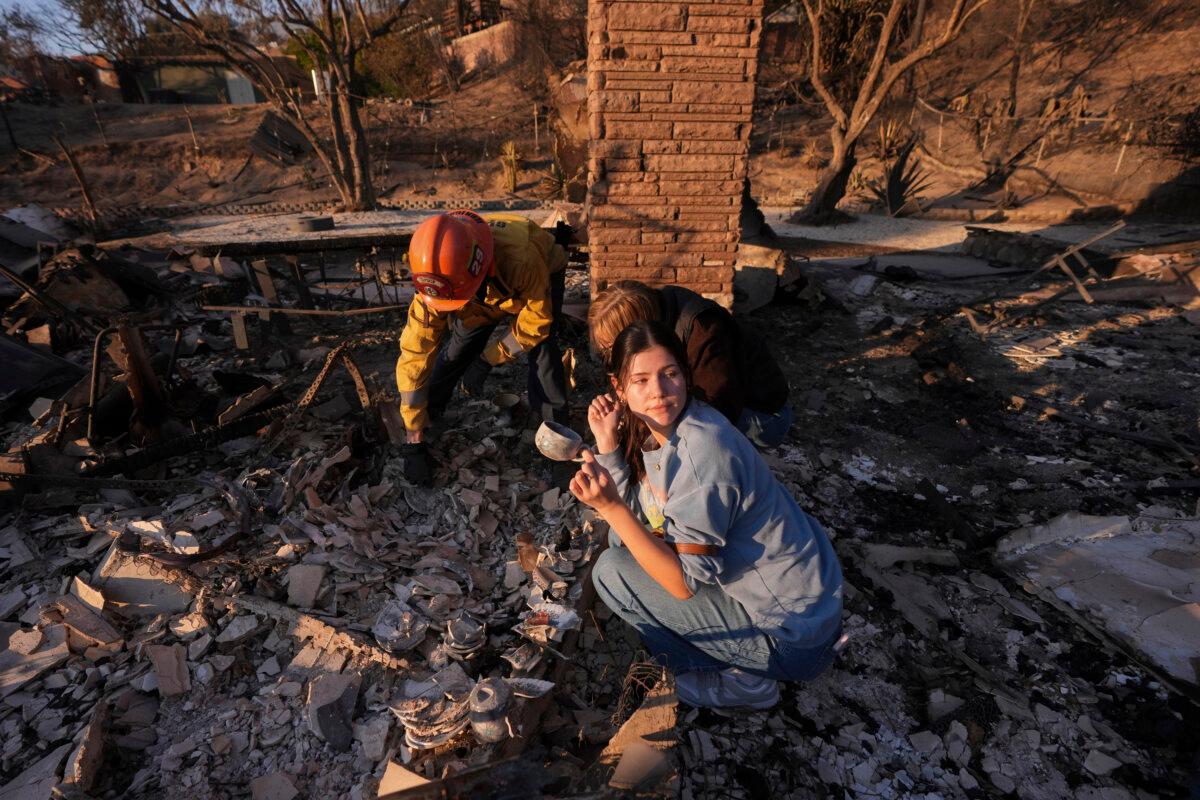 Ella Venne holds a cup she found in the remains of her family's home destroyed by the Eaton Fire as she searches with Glendale Fire Department captain Chris Jernegan (L) and his wife Alison in Altadena, Calif., on Jan. 11, 2025. (Mark J. Terrill/AP Photo)