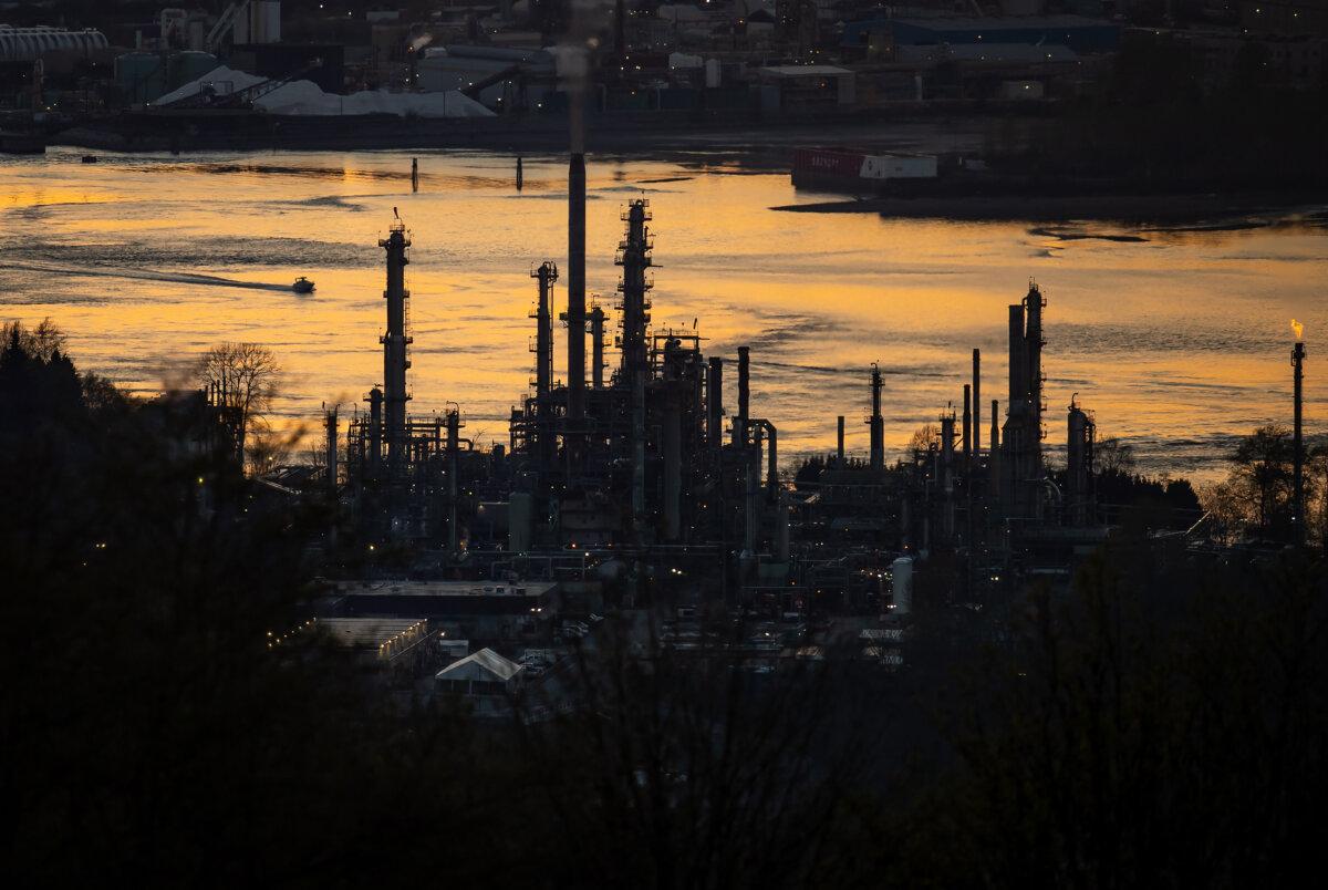 A boat travels past a refinery at sunset in Burnaby, B.C., in a file photo. (Darryl Dyck/The Canadian Press)