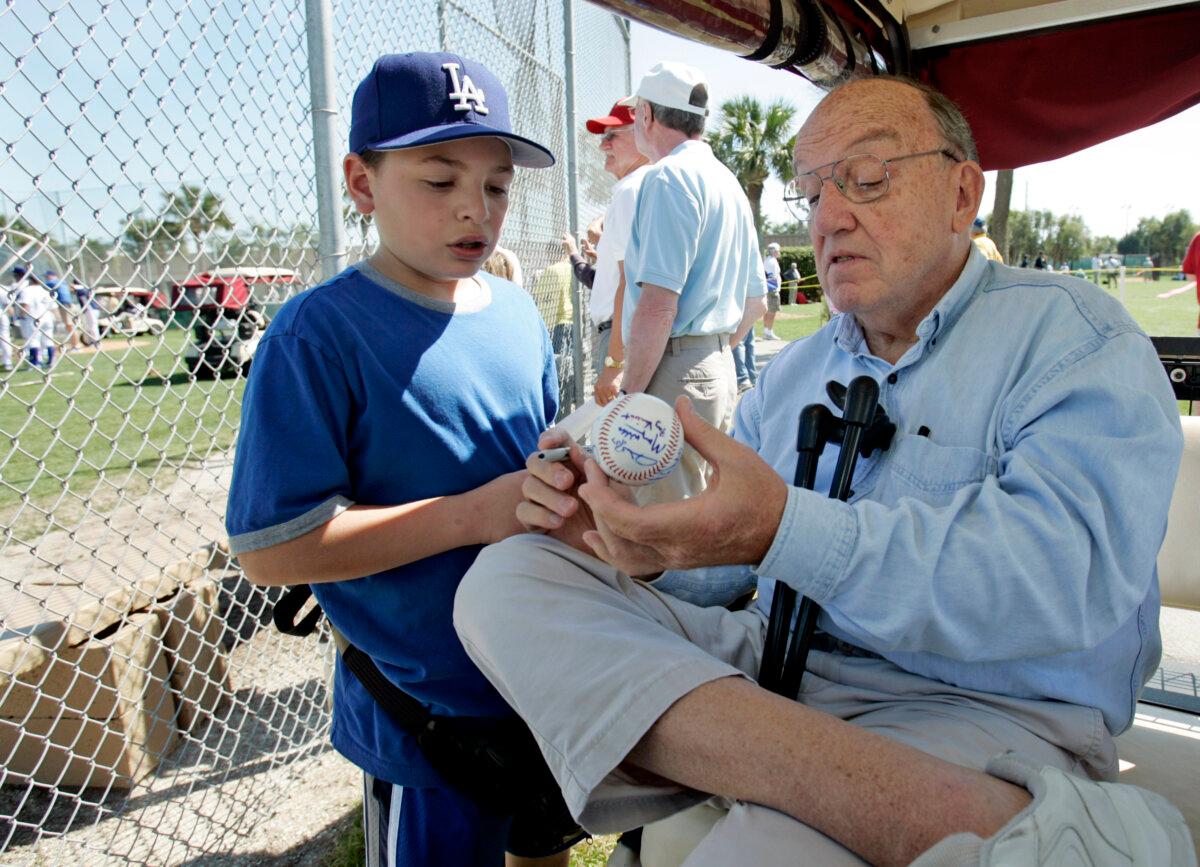 Former Major League Baseball Commissioner Fay Vincent signs an autograph for Louis Carrons, 12, of Rancho Cucamonga, Calif., during Los Angeles Dodgers baseball spring training in Vero Beach, Fla., on March 1, 2006. (Richard Drew/AP Photo)