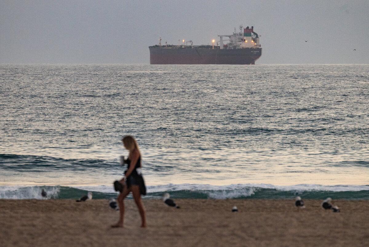 A beachgoer in view of oil shipment and production vessels in Huntington Beach, Calif., on Sept. 12, 2024. (John Fredricks/The Epoch Times)