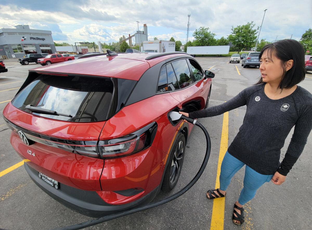 A woman uses an electric vehicle charging station at a Canadian Tire in Scarborough, Ont., on June 14, 2023. (The Canadian Press/Doug Ives)