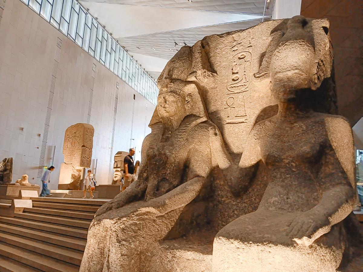 Visitors admire statues on the grand staircase inside the new Grand Egyptian Museum on April 25, 2025. (Autumn Spredemann/The Epoch Times)
