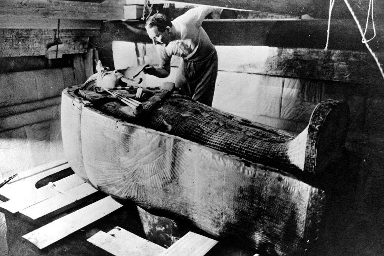 Howard Carter examining Tutankhamun’s tomb. (Public Domain)