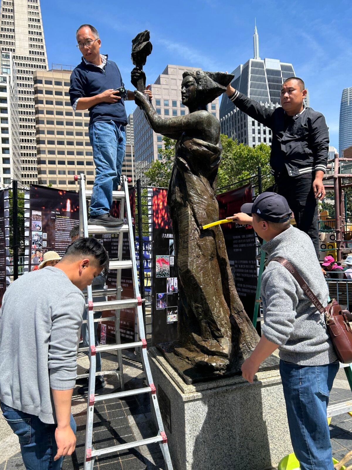 Chinese pro-democracy activists clean the bronze statue of the Goddess of Democracy in Portsmouth Square in San Francisco on May 25, 2025. (Nathan Su/The Epoch Times)