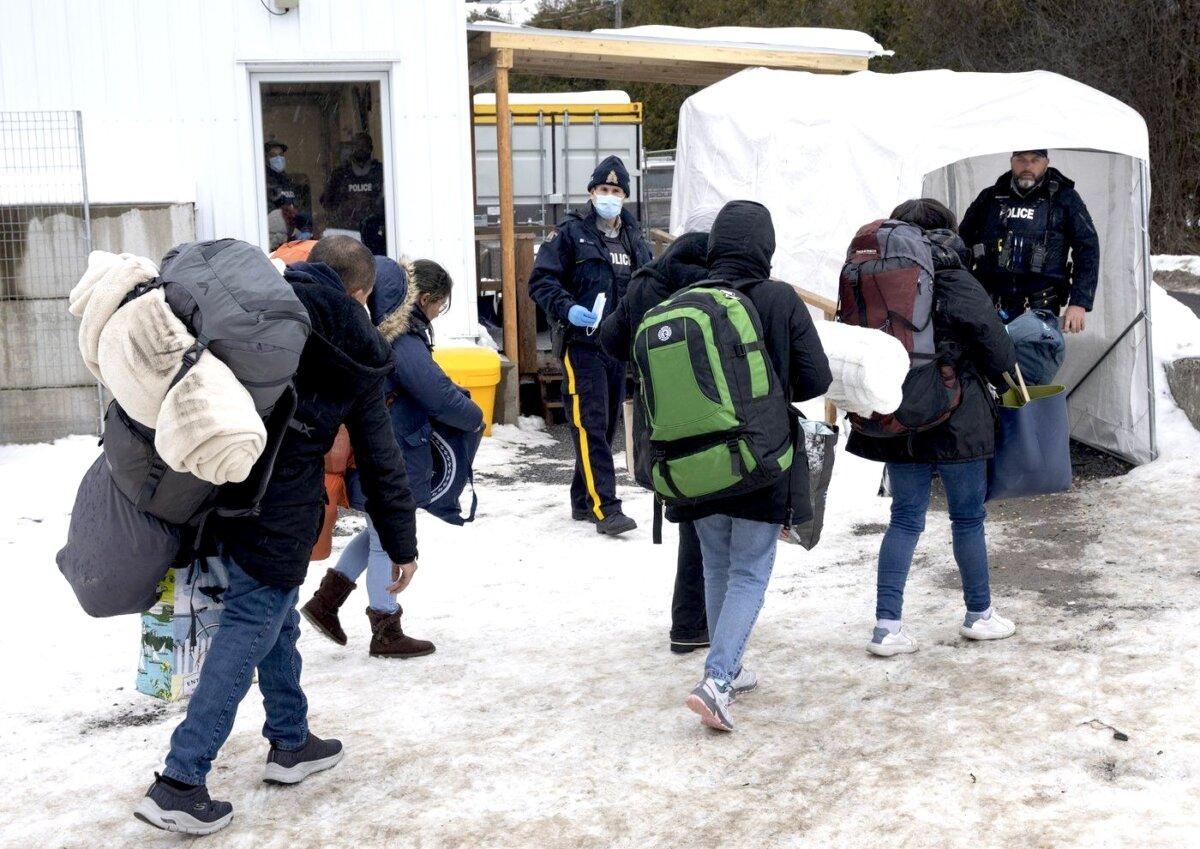 Asylum-seekers are met by RCMP officers after crossing the Canada-U.S. border at Roxham Road, Quebec, into Canada on Feb. 9, 2023. (The Canadian Press/Ryan Remiorz)